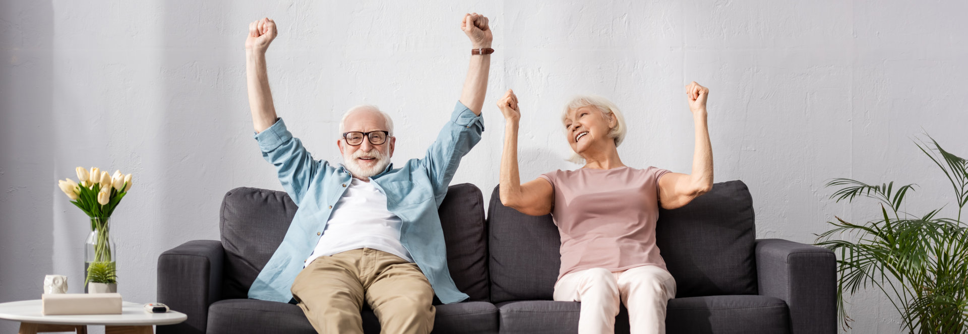 elderly couple raise their hands and smiling